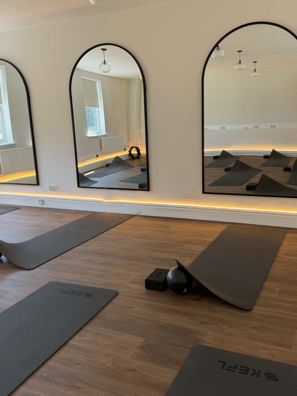 Studio mats and equipment beneath arched mirrors